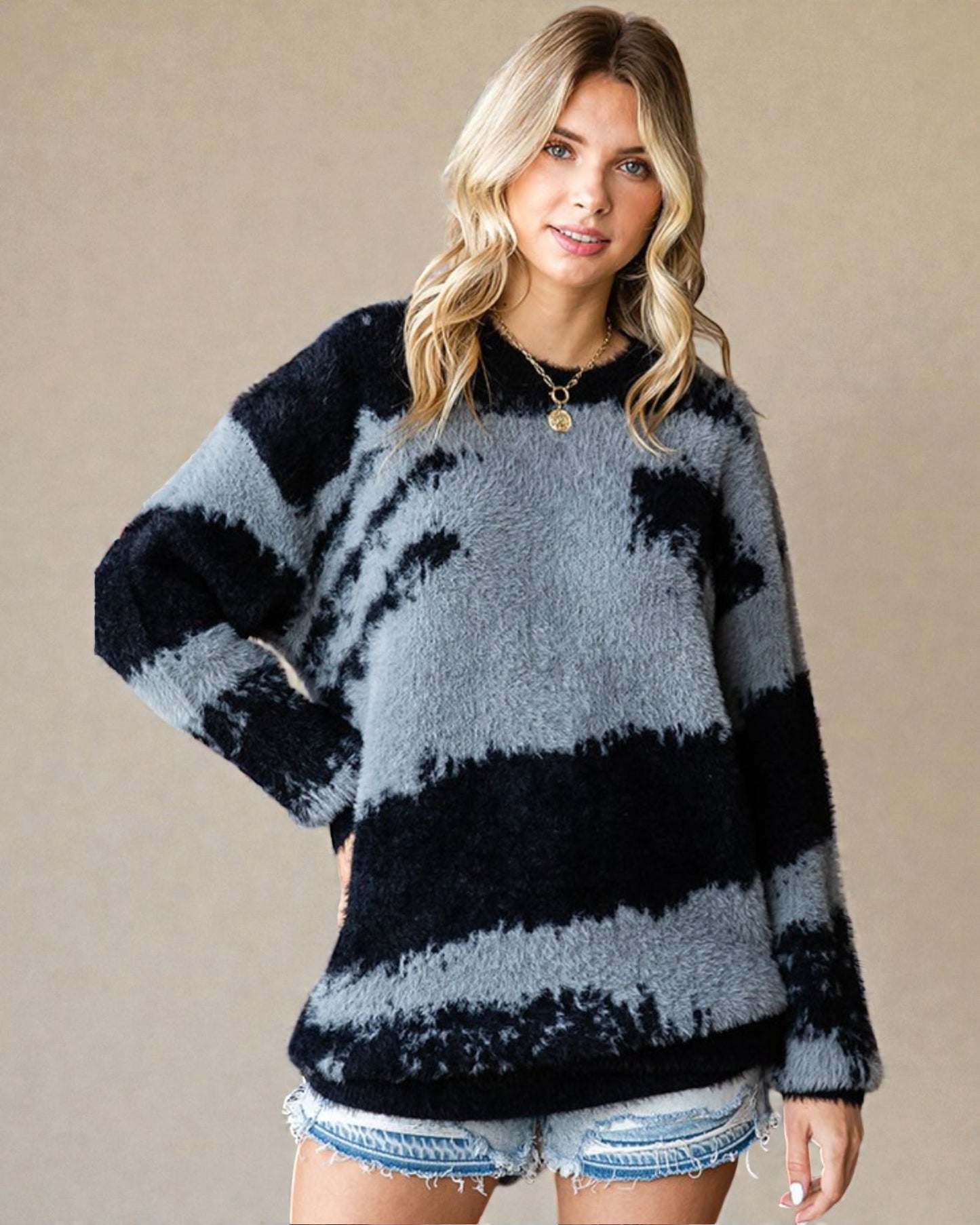 Woman wearing a black and gray tie-dye sweater against a beige background