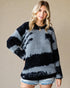 Woman wearing a black and gray tie-dye sweater against a beige background