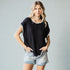 Woman wearing a black top with white trim and denim shorts on a gray background
