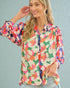 Woman wearing a colorful floral blouse against a light blue background