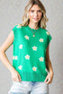Woman wearing a green sleeveless top with white floral patterns on a gray background