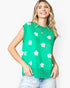 A woman wearing a bright green sleeveless knit top with a white and yellow flower pattern, paired with light-wash jeans, against a plain white background.
