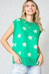 Woman wearing a green sleeveless top with floral patterns against a light background