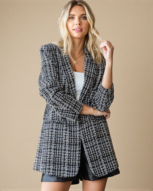Woman wearing a black and white checkered coat against a beige background