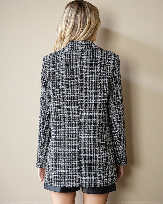 Person wearing a black and white checkered blazer against a beige wall