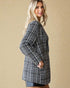 Woman wearing a black and white checkered coat against a beige background