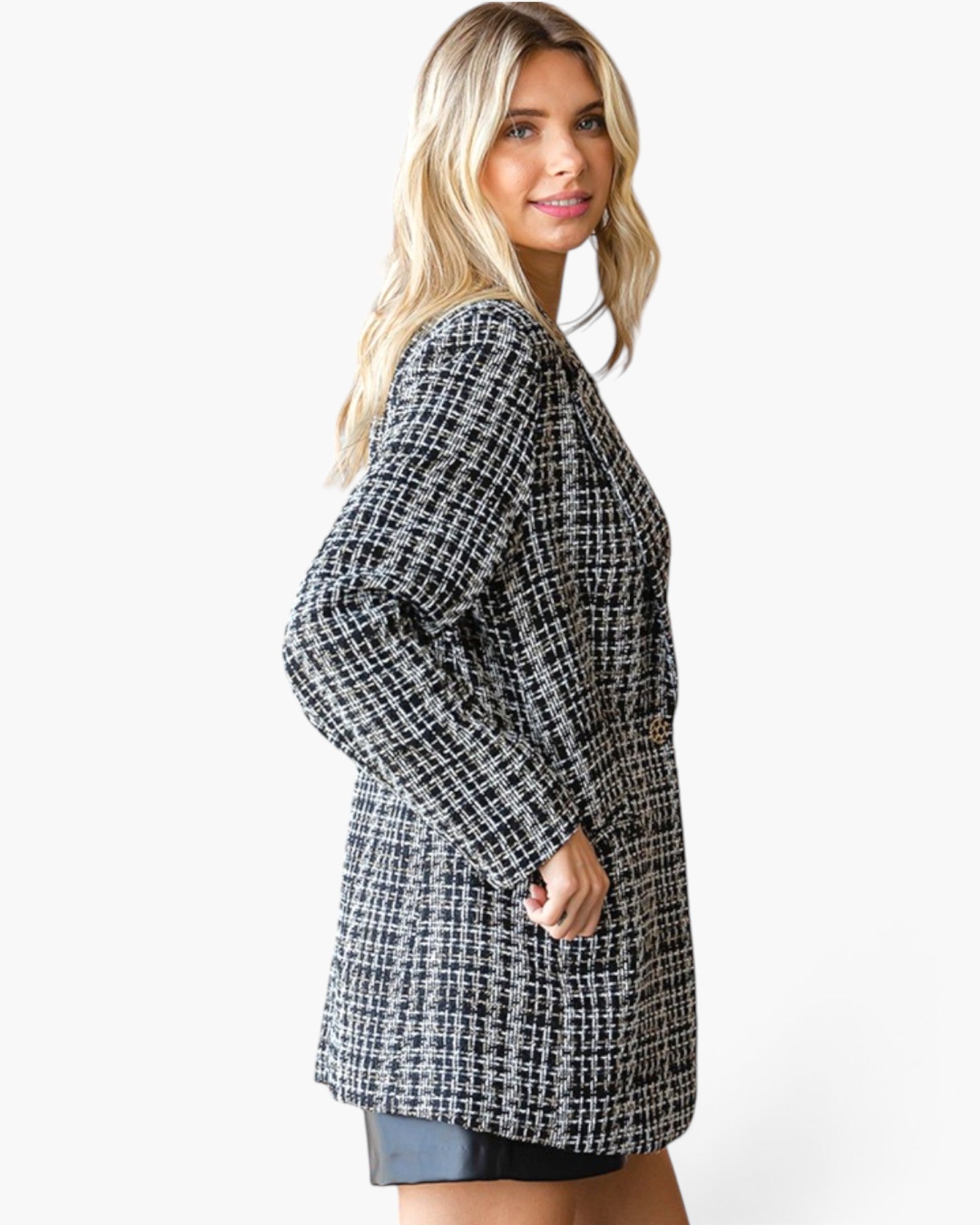 A woman wearing a black and white houndstooth tweed long-sleeve tunic dress, shown from a side-back angle against a plain white studio background.
