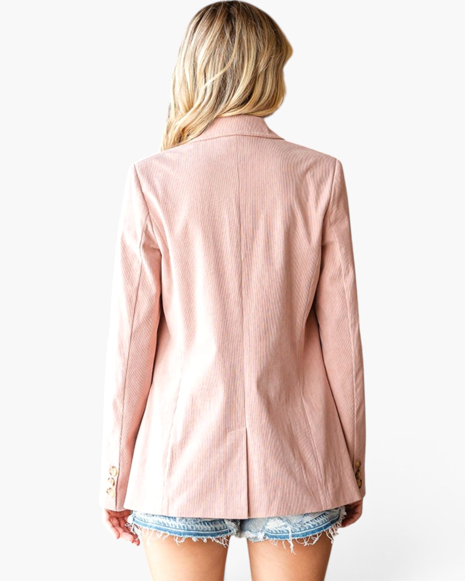 A woman shown from the back wearing a light pink corduroy blazer and denim shorts against a plain white background.