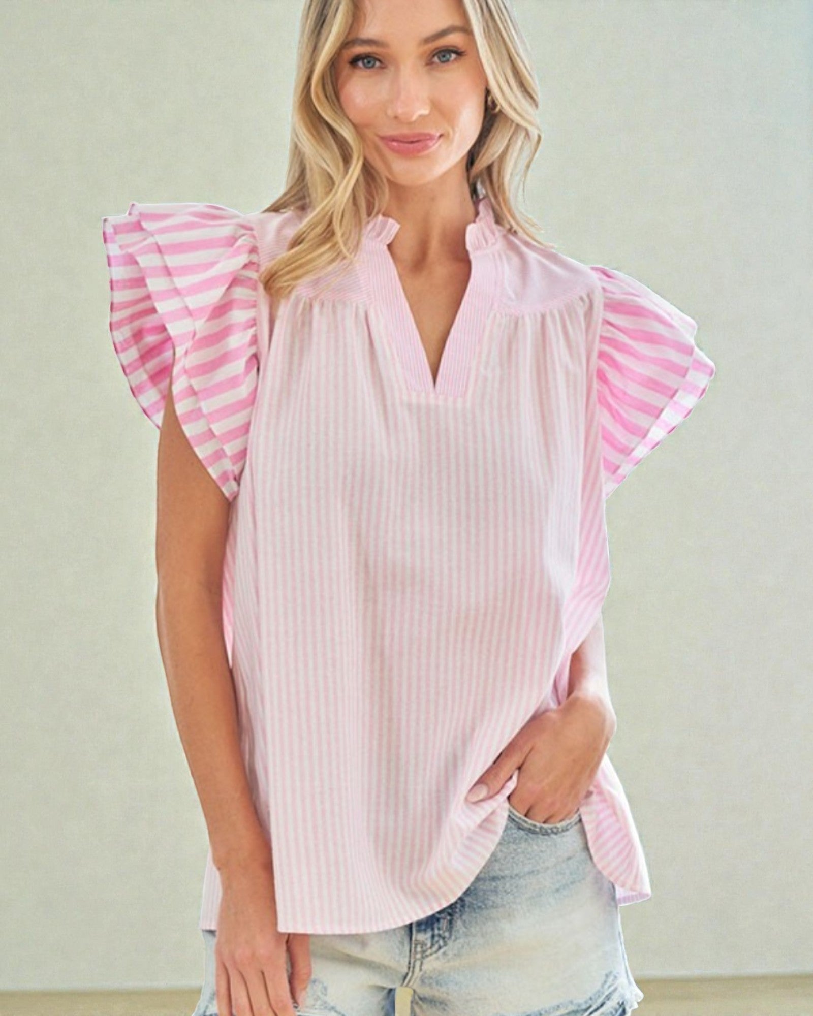 Woman wearing a pink blouse with ruffled sleeves against a plain background