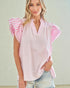 Woman wearing a pink blouse with ruffled sleeves against a plain background