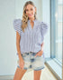 Woman wearing a blue and white striped shirt and denim shorts indoors.