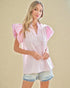 Woman wearing a white blouse with pink ruffled sleeves on a beige background