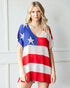 Woman wearing a colorful dress with star and stripe pattern against a white wall.
