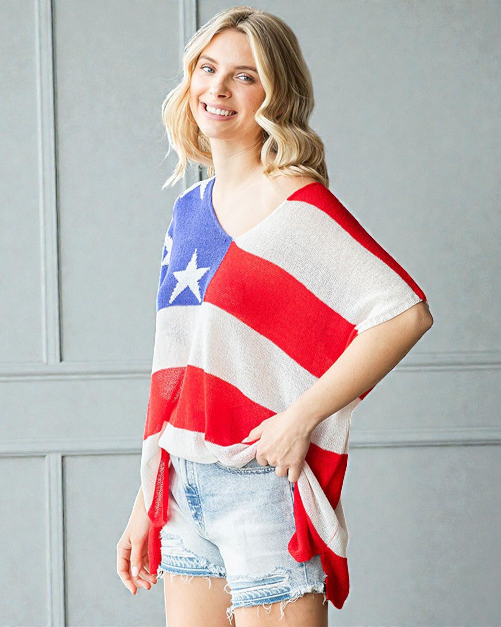 Woman wearing a American flag shirt against a gray wall