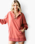 A woman modeling a dusty rose long-sleeve pullover sweatshirt with a buttoned henley collar, front pockets, and a frayed hem, set against a plain white studio background.