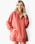 A woman wearing a dusty coral pink long-sleeve button-up pullover sweatshirt with a split kangaroo pocket, shown against a plain white studio background.