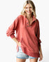 A woman wearing a dusty rose long-sleeve quarter-placket pullover sweatshirt with denim shorts, standing against a plain white studio background.