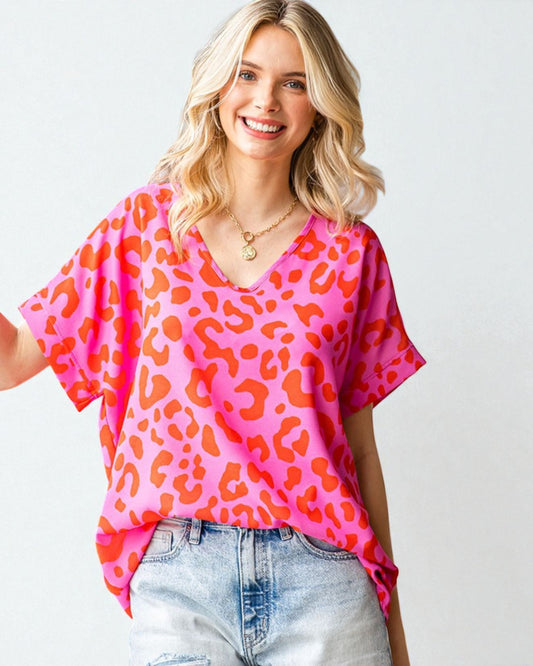 Woman wearing a pink leopard print top and light blue jeans on a white background