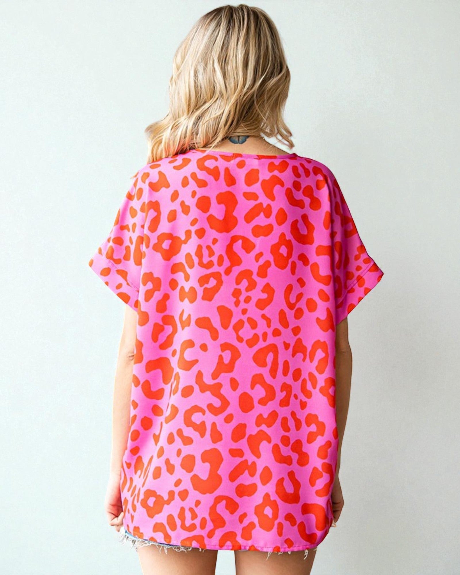 Person wearing a pink leopard print dress against a white background
