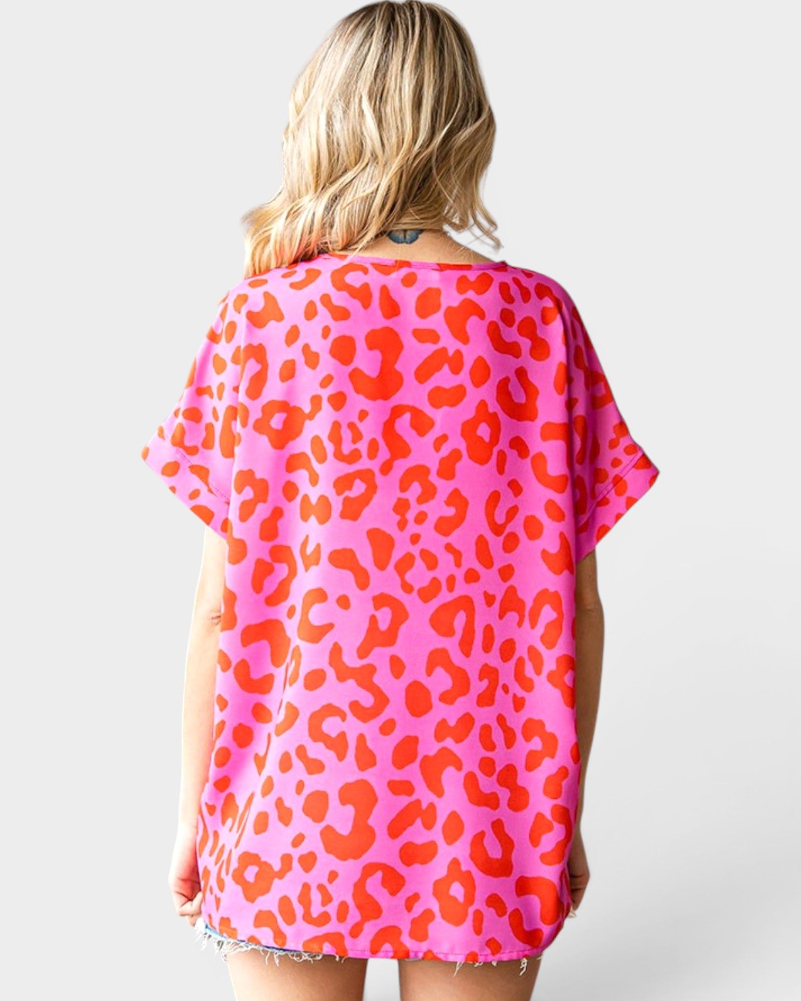 Person wearing a pink and orange leopard print top on a white background