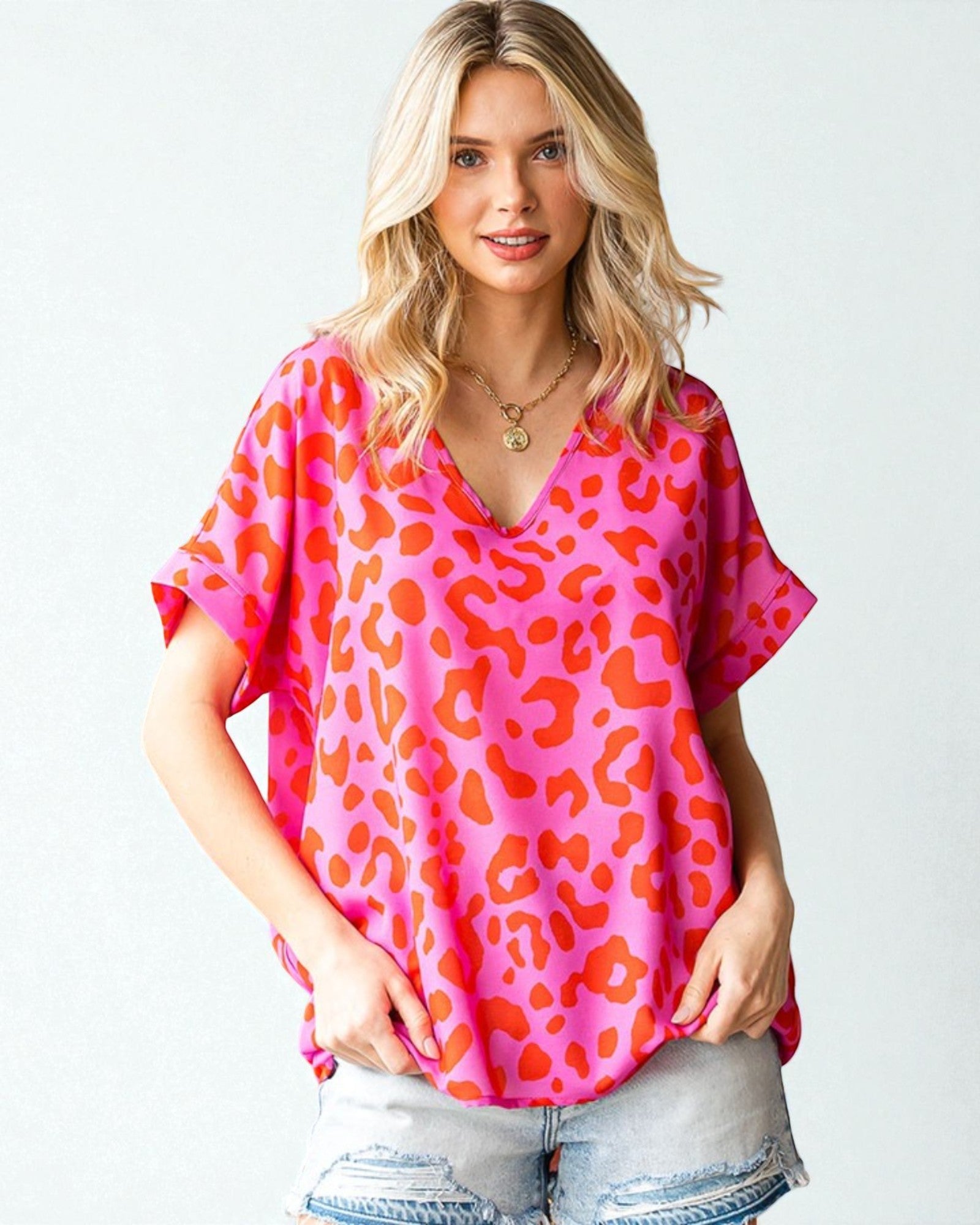 Woman wearing a pink and orange leopard print top on a white background