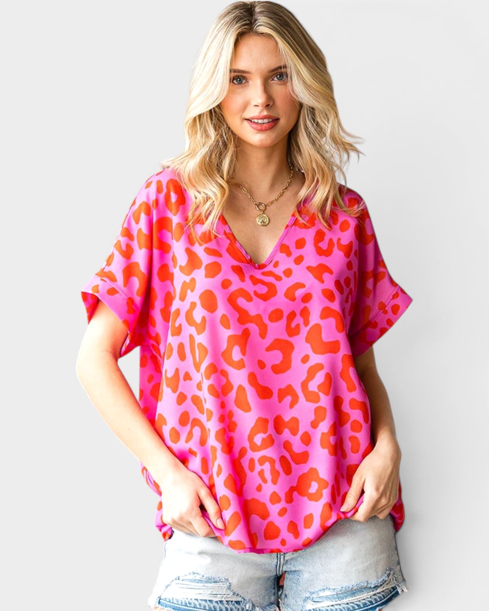 Woman wearing a pink leopard print top against a white background