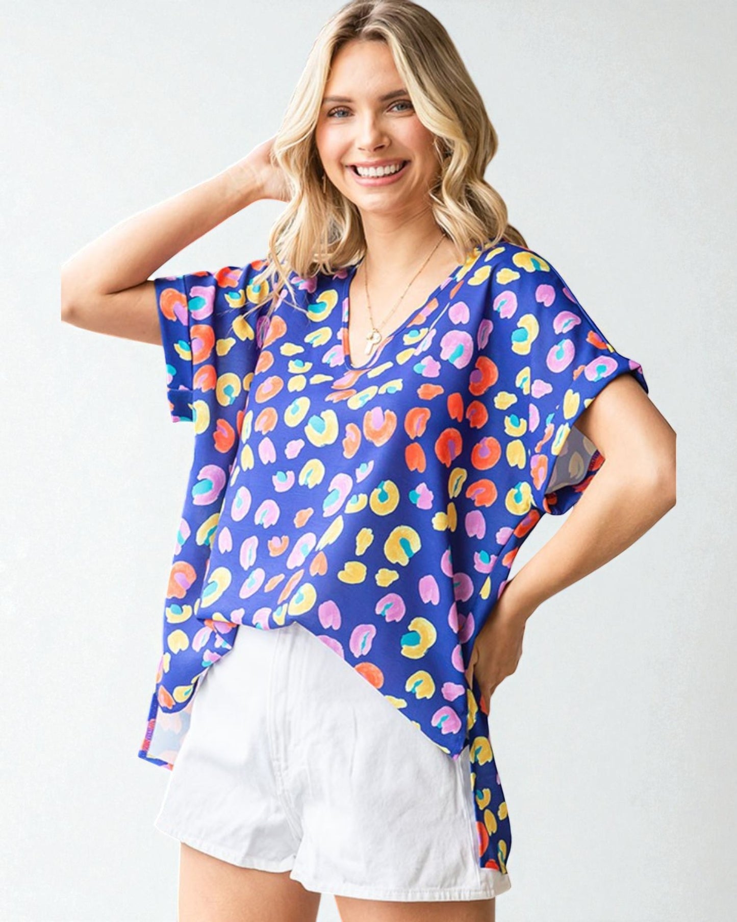 Woman wearing a colorful patterned top with a plain background