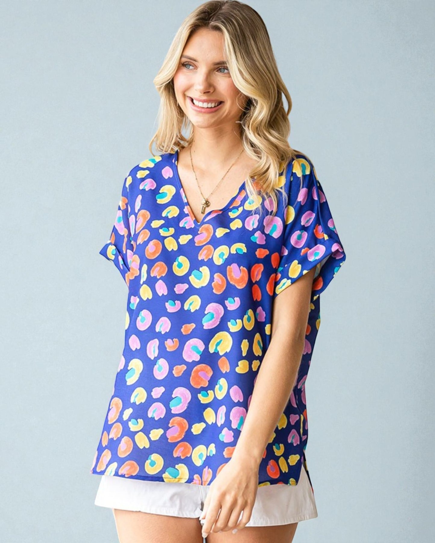 Woman wearing a colorful patterned top against a light gray background