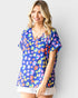 Woman wearing a colorful patterned shirt against a plain background