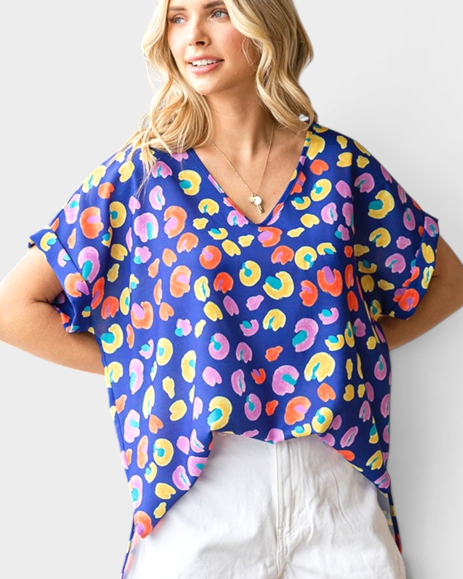 Woman wearing a colorful patterned top with a plain background