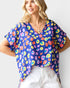 Woman wearing a colorful patterned top with a plain background