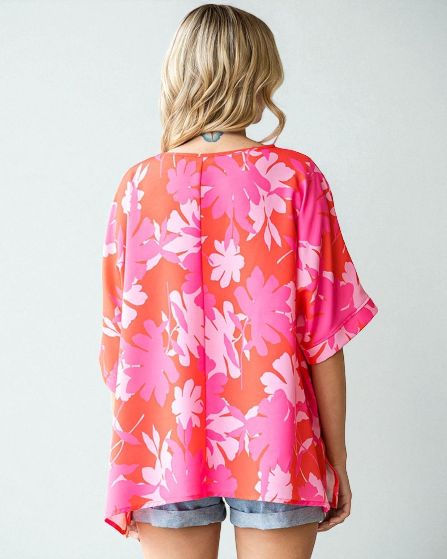 Woman wearing a pink floral kimono-style top on a white background