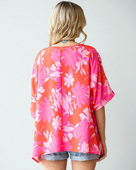 Woman wearing a pink floral kimono-style top on a white background
