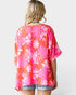Woman wearing a pink floral kimono-style top on a white background