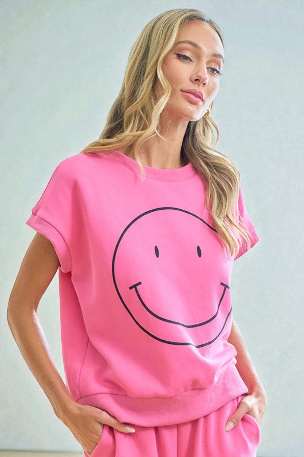 Woman wearing a pink outfit with a smiley face design against a light background
