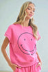 Woman wearing a pink outfit with a smiley face design against a light background