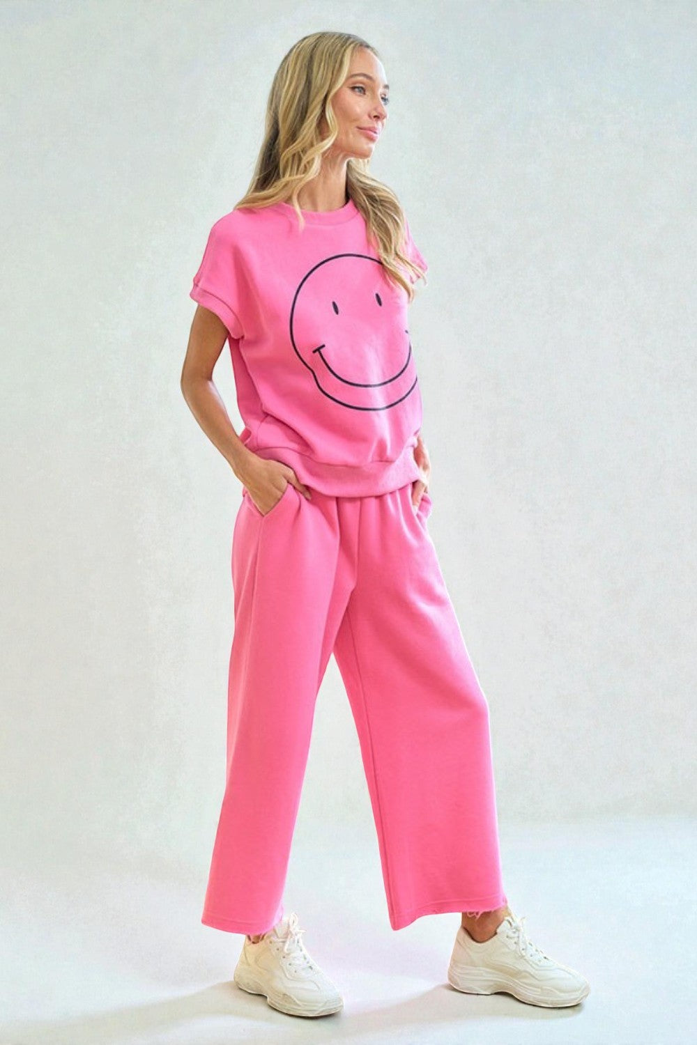 Person wearing a pink outfit with a smiley face design on a plain background