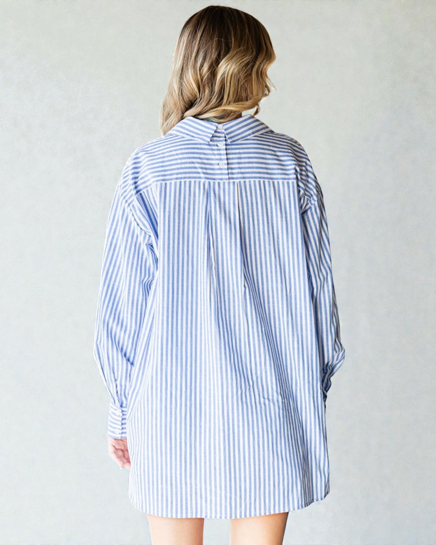 Person wearing a blue and white striped shirt dress against a plain background