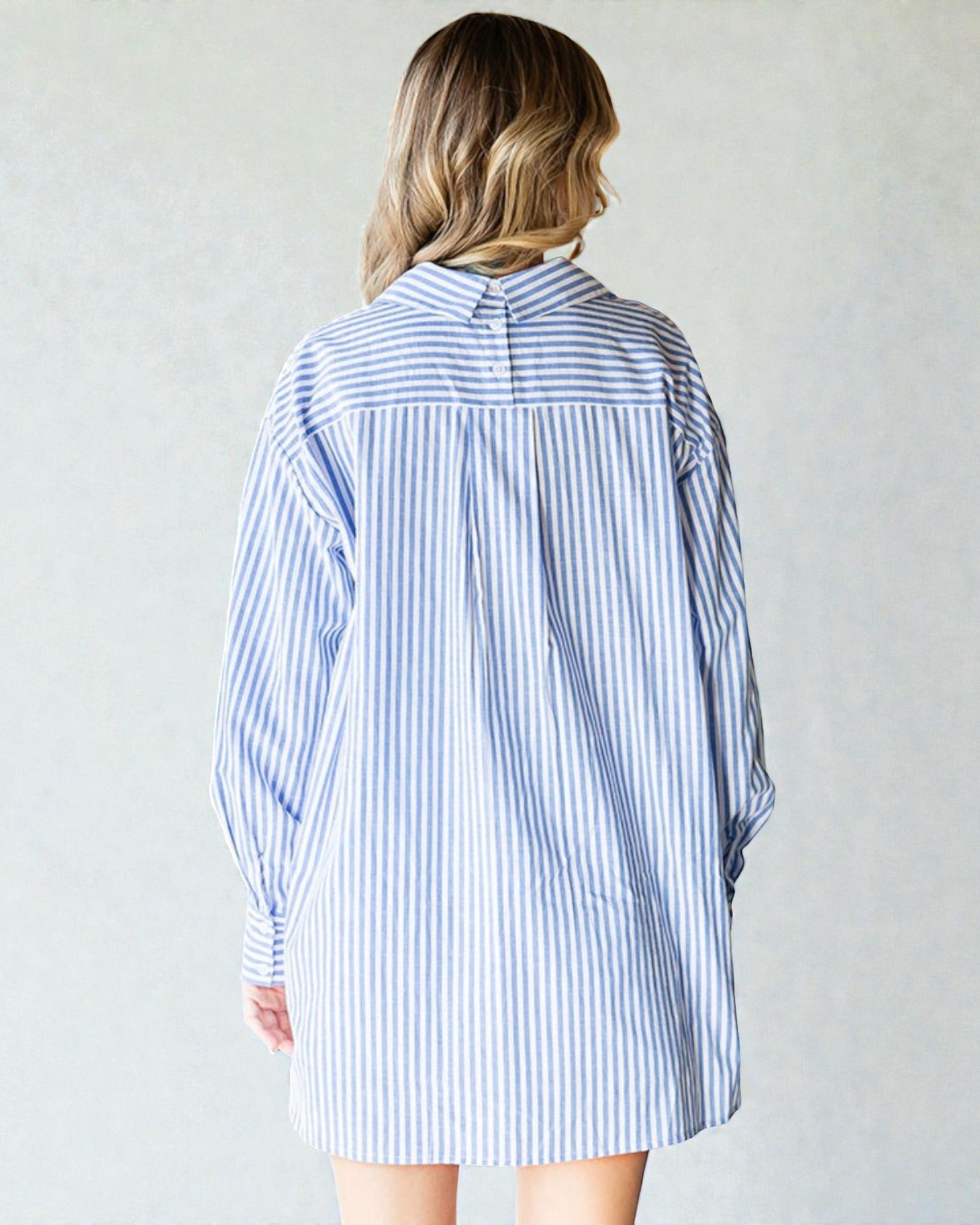Person wearing a blue and white striped shirt dress against a plain background