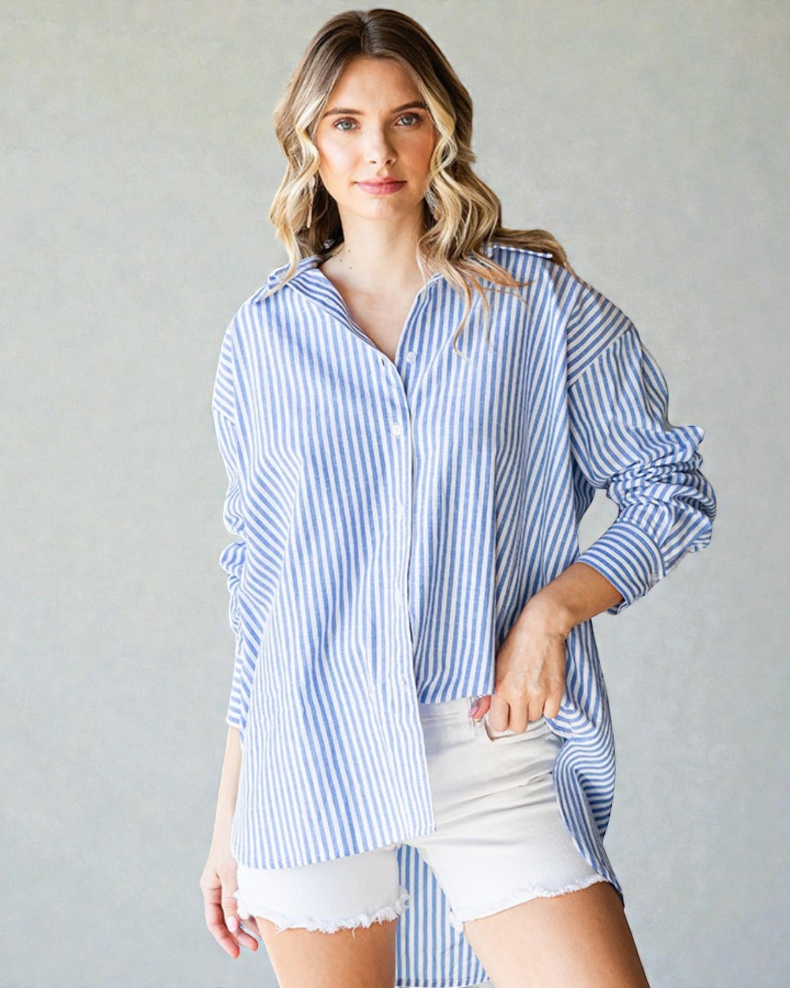 Woman wearing a blue and white striped shirt with white shorts on a plain background