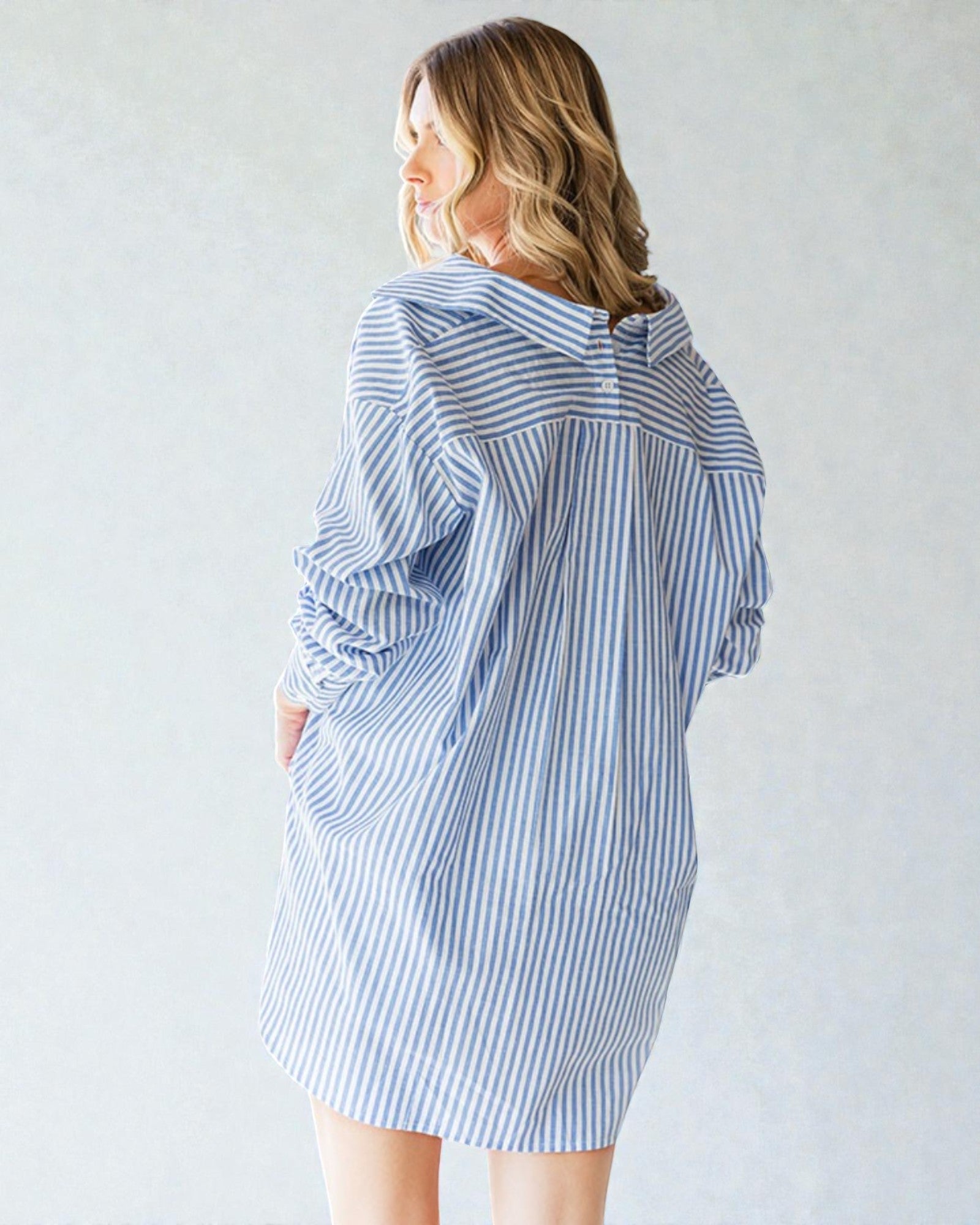 Woman wearing a blue and white striped dress against a plain background
