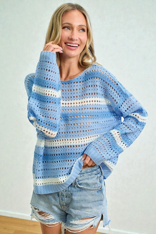 Woman wearing a blue and white striped crochet sweater with denim shorts against a light background