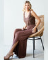 Woman in a brown dress sitting on a wicker chair against a white background