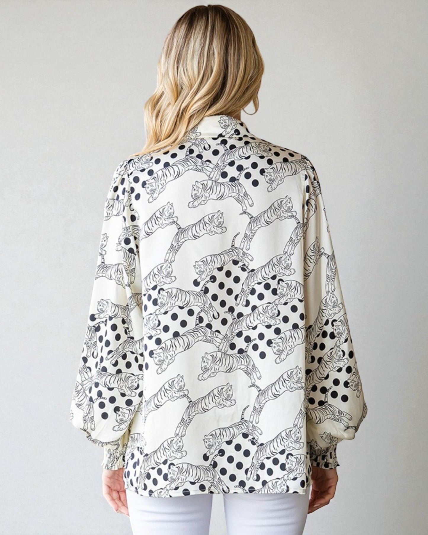 Woman wearing a patterned blouse with tigers and polka dots on a plain background