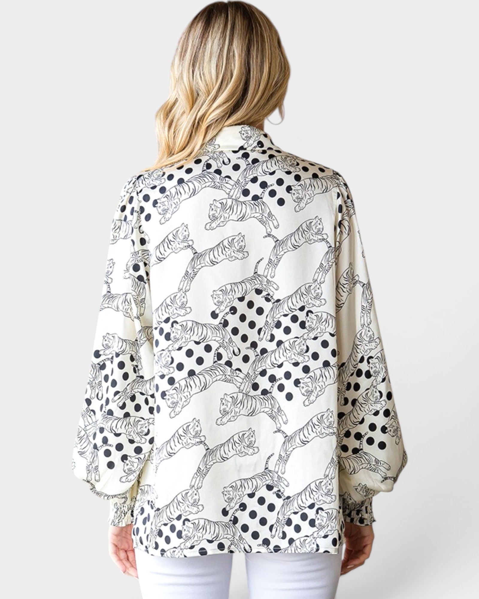 Woman wearing a patterned blouse with black and white designs on a plain background