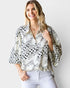 Woman wearing a patterned blouse with a plain background