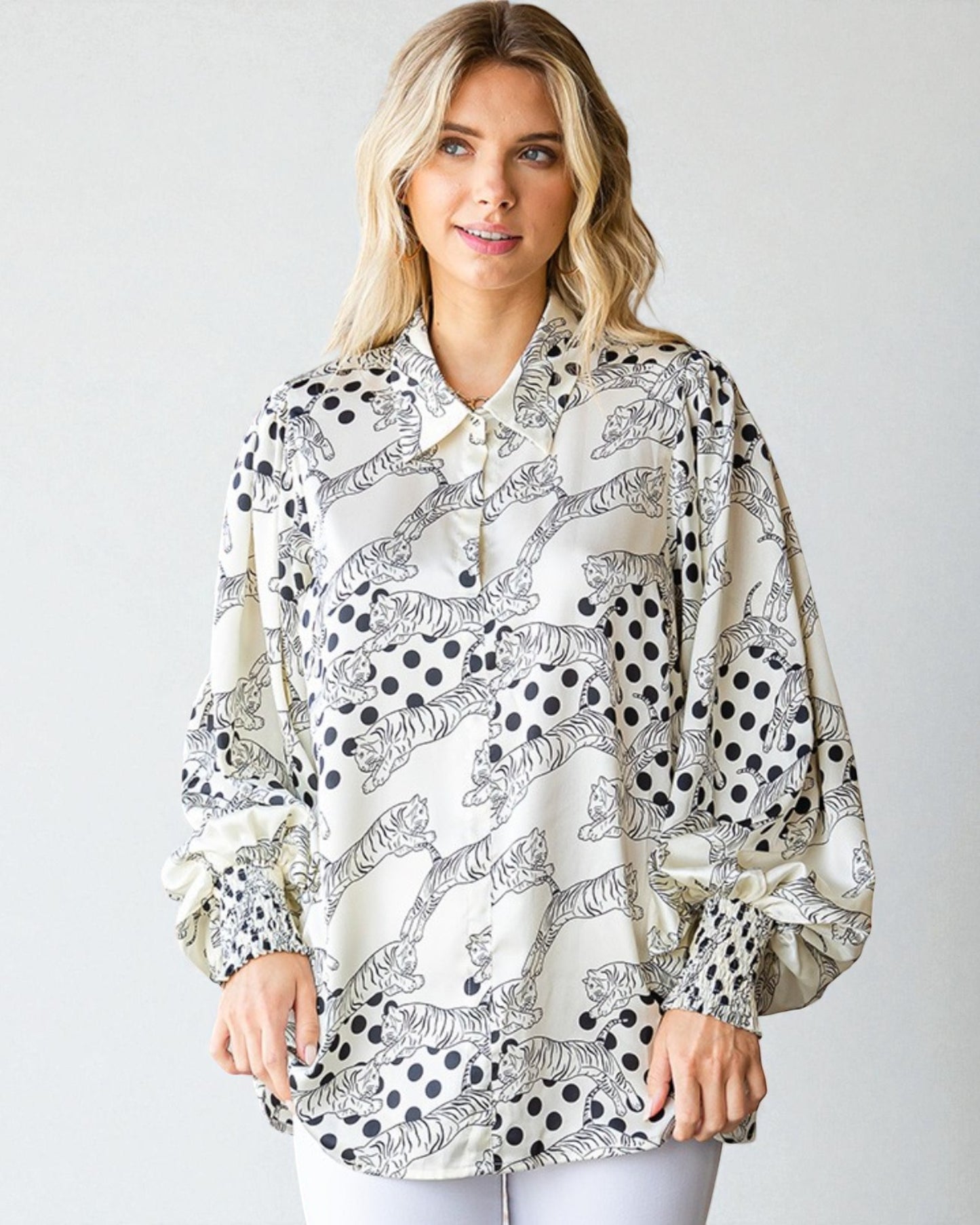 Woman wearing a patterned blouse with long sleeves on a plain background