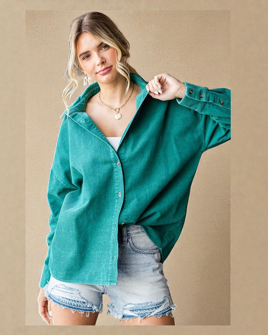 Woman wearing a teal jacket and denim shorts on a beige background