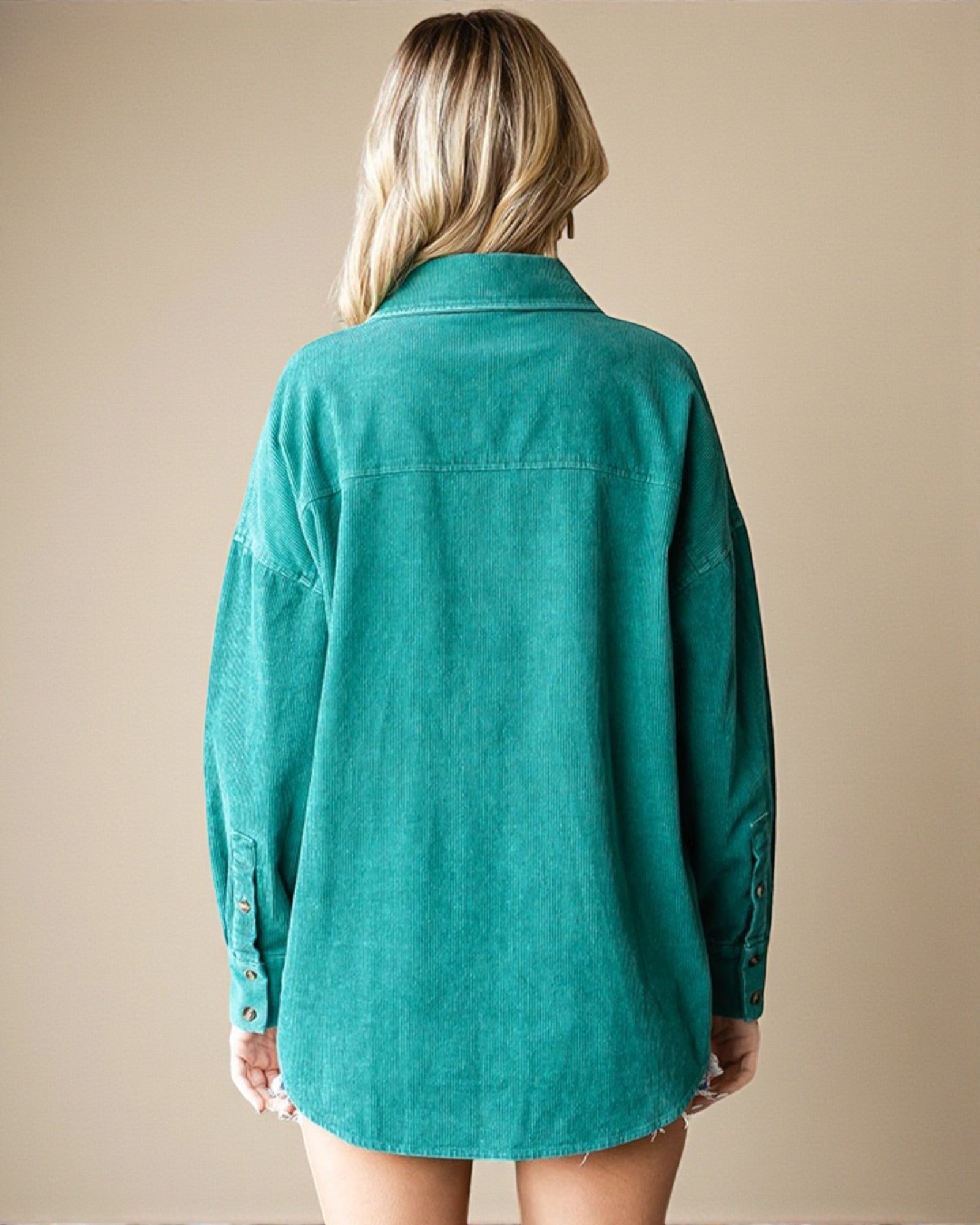 Person wearing a teal shirt against a beige background