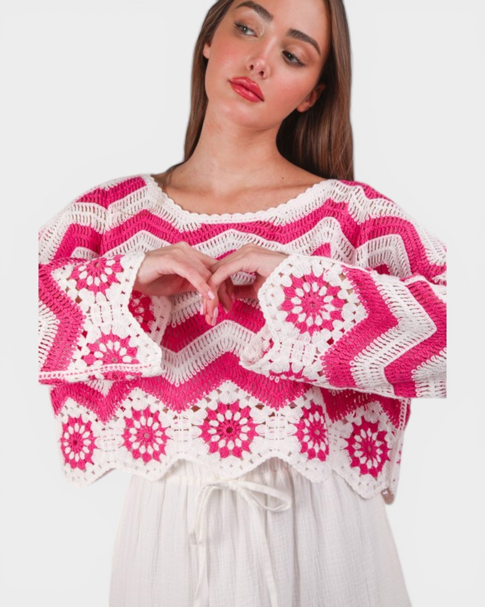 Woman wearing a pink and white patterned crochet top on a white background